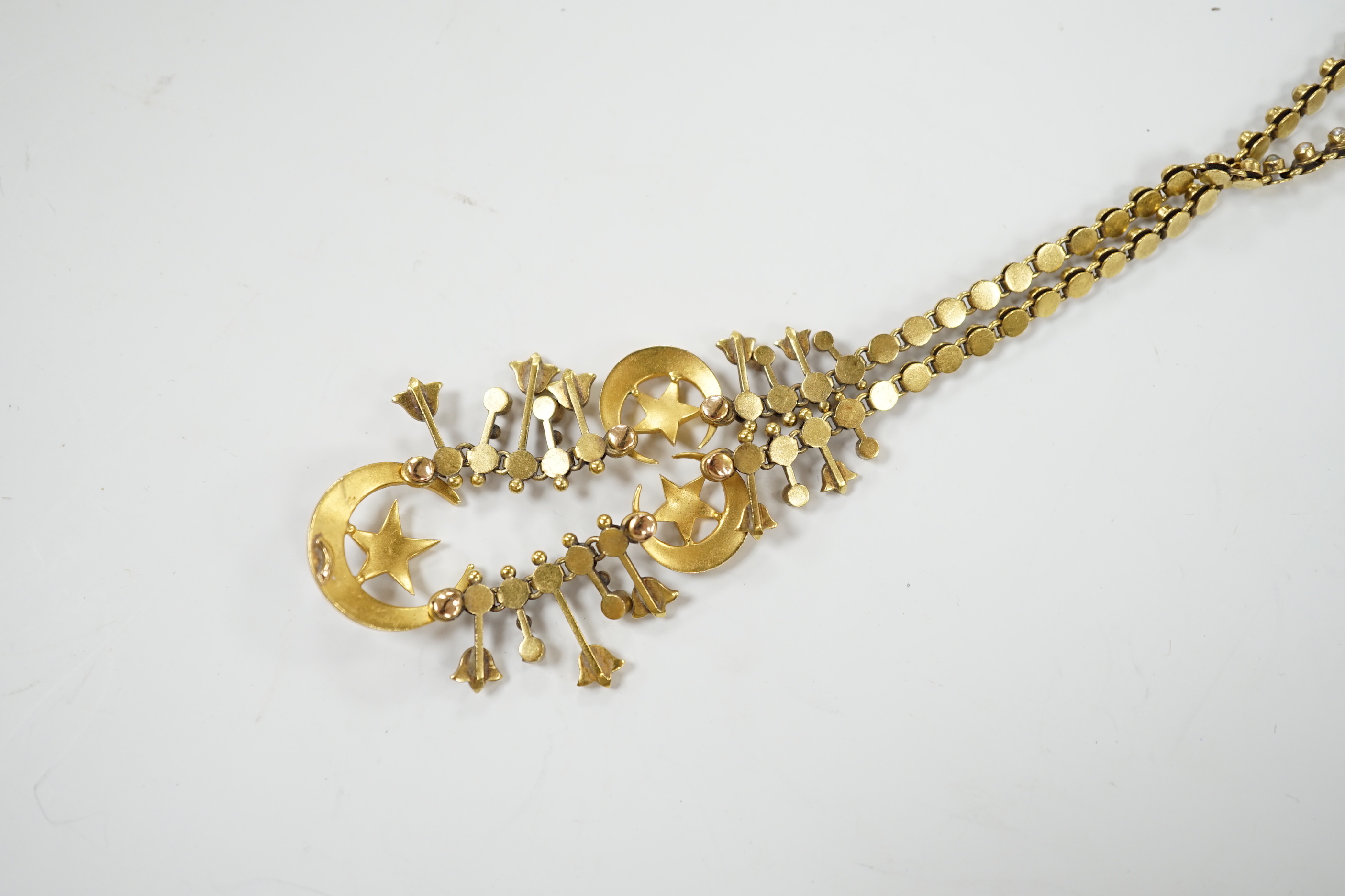 An Edwardian yellow metal and seed pearl set drop necklace, with star and crescent motifs, lacking central drop, 38cm, gross weight 16.3 grams.